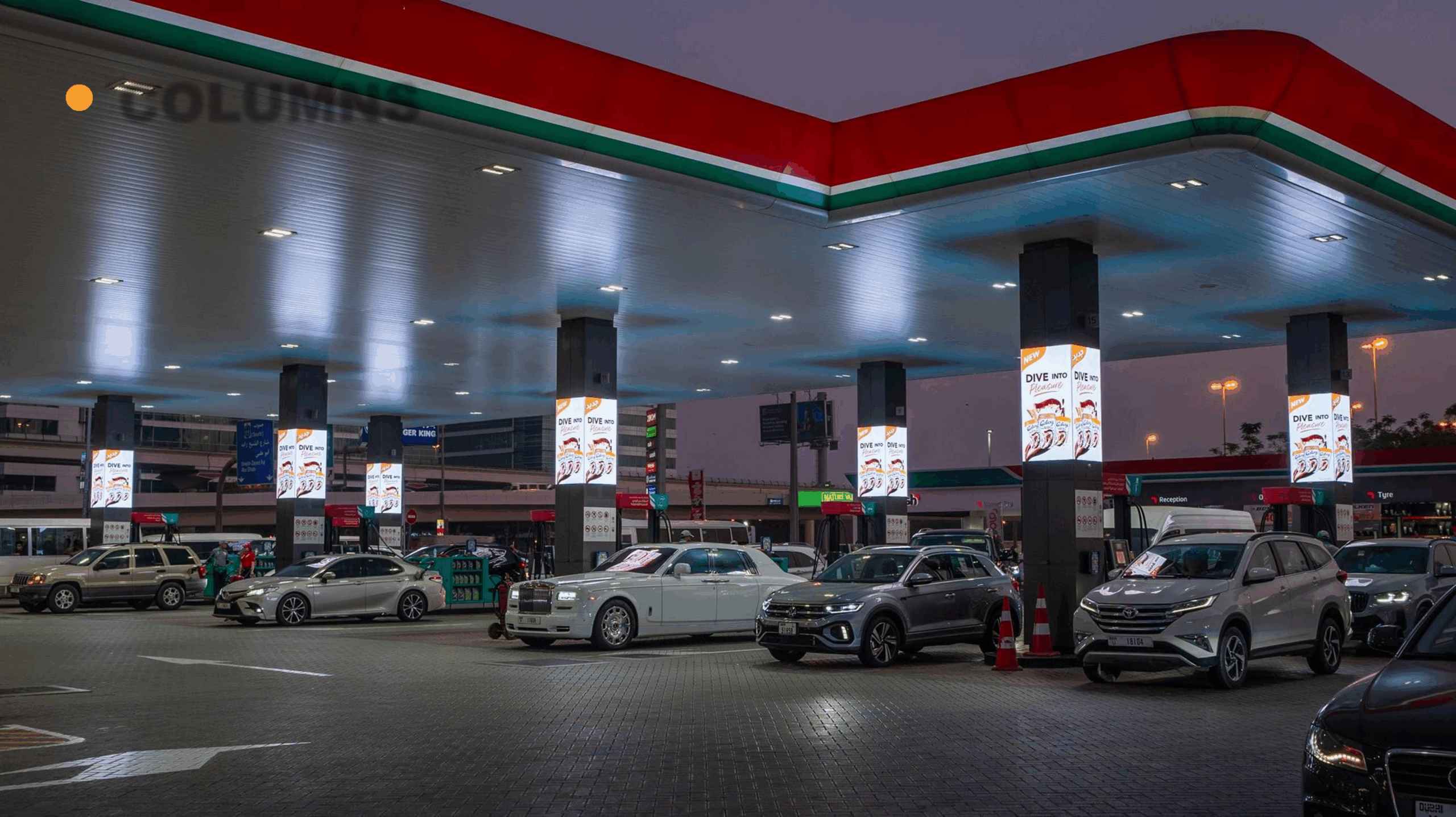 Column-mounted digital advertising screens at an ENOC gas station in Dubai, showcasing high-impact transit media campaigns.