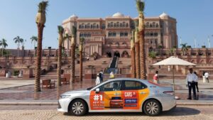 Vibrant dual-language transit media sticker display on a public transport taxi driving across modern Dubai communities