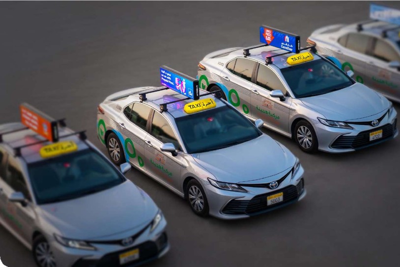 A fleet of Abu Dhabi Tawasul taxis displaying programmatic digital rooftop advertising screens in the UAE