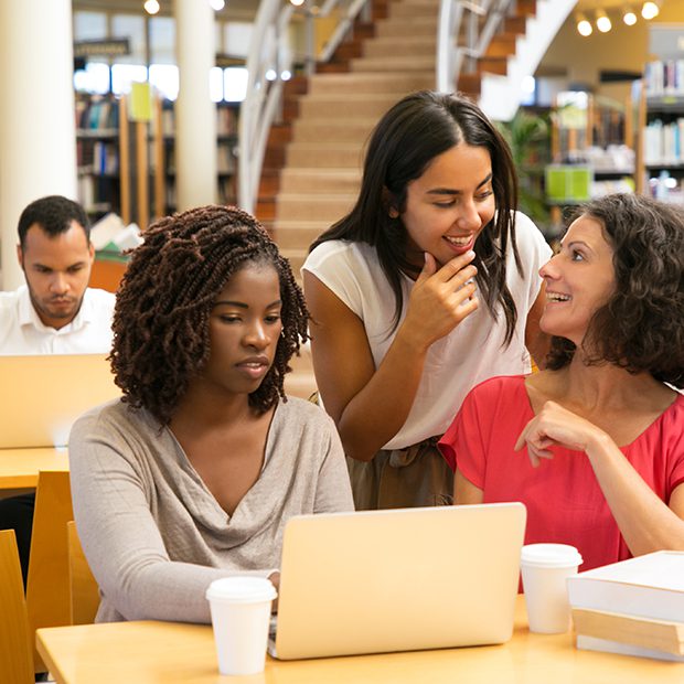 Diverse students studying together in library