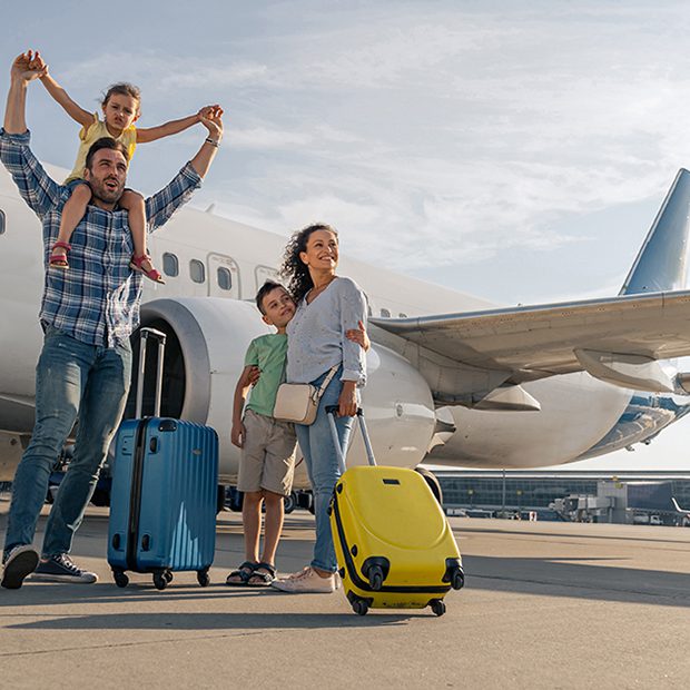 Happy family with suitcases boarding airplane on runway