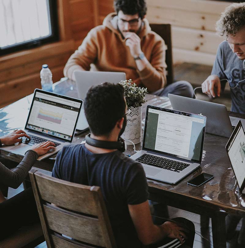 Creative agency team working on laptops around office table