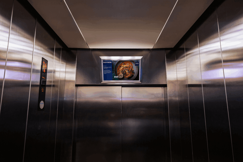 Digital advertising screen mounted inside a premium stainless-steel elevator for captive audience marketing in Dubai