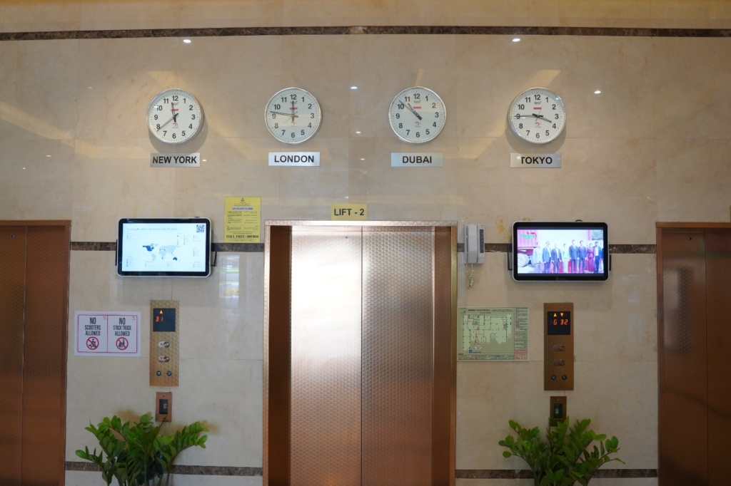 Digital advertising screens installed in a premium international corporate office lobby next to elevator doors in Dubai