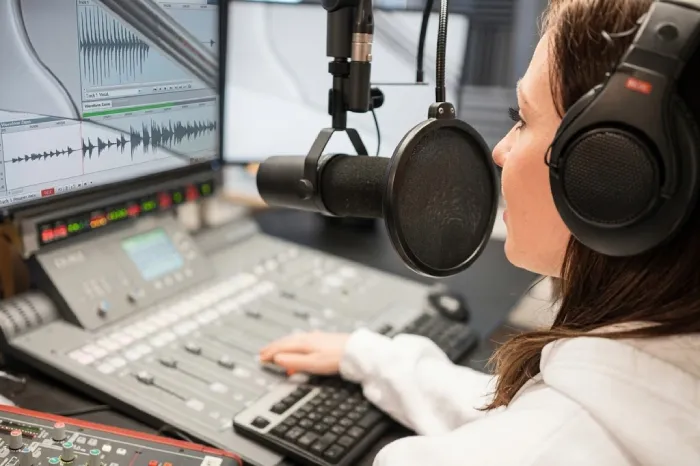 Female jockey speaking into microphone at radio station recording studio