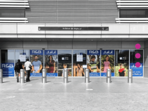 Outdoor transit advertising display featuring fashion brand promotional graphics at a major Dubai Metro station entrance.