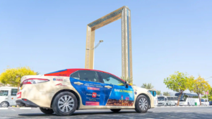 MakeMyTrip branded RTA taxi parked in front of Dubai Frame