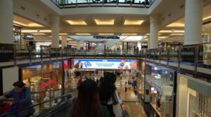 Large horizontal digital advertising screen displaying a brand campaign inside the atrium of City Centre Mall