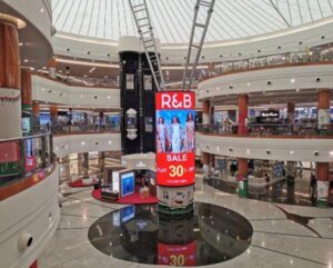 Vertical digital screen advertising pillar inside a shopping mall in Dubai and Abu Dhabi showcasing retail branding