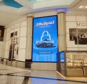 Large vertical digital screen displaying promotional advertising content inside a premium shopping mall